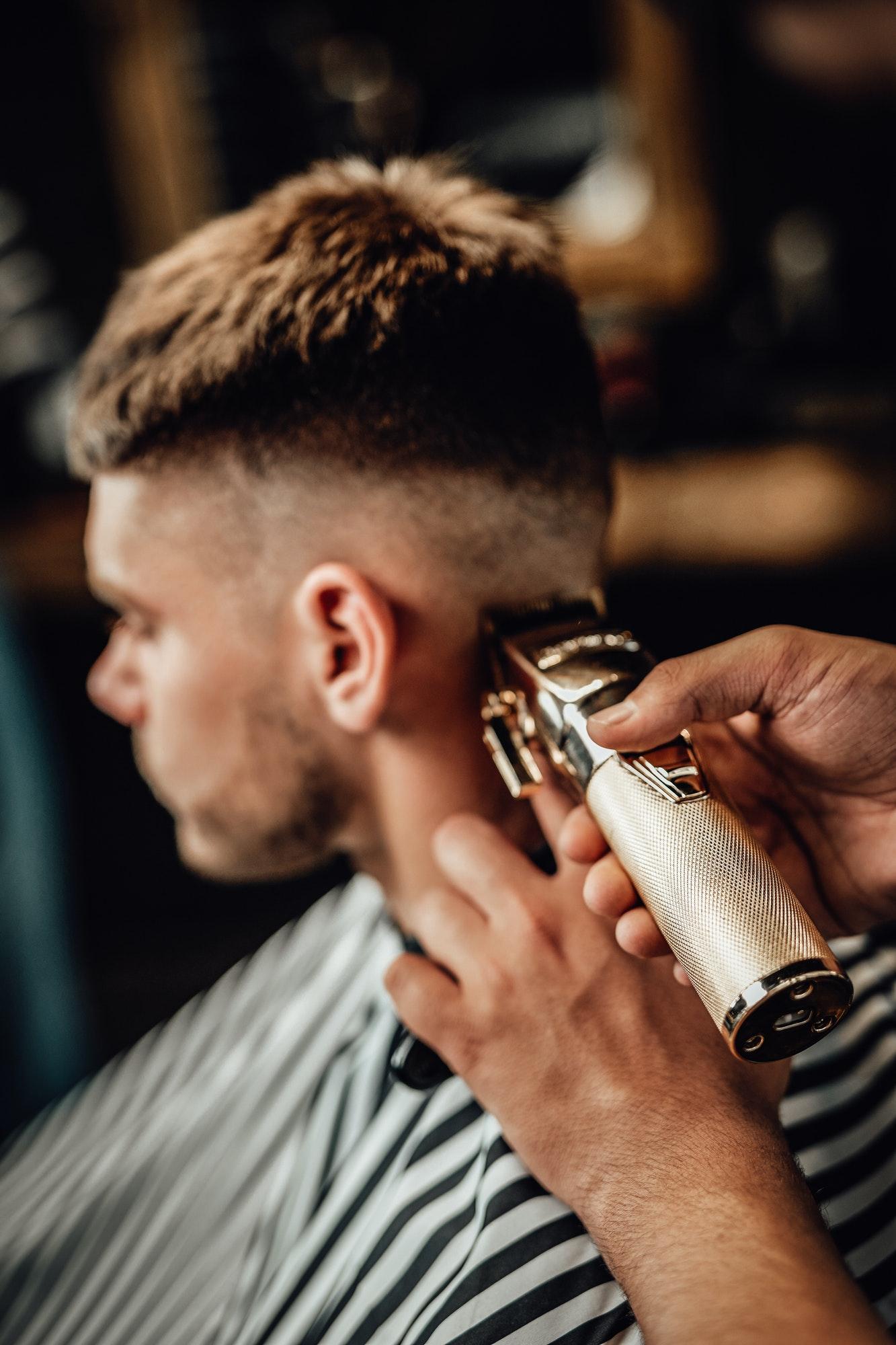 En barberare trimmar en mans frisyr
